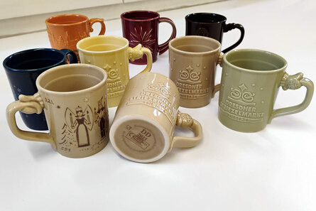 Verschiedene, bunte Glühweintassen der sächsischen Weihnachtsmärkte