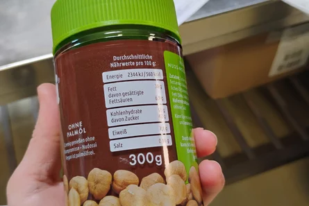 Eine Hand hält ein Glas Nuss-Nougat-Creme. Zu erkennen ist unter anderem die Inhaltsangabe: 300 Gramm.